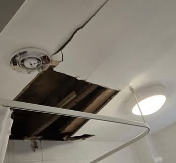 Bathroom ceiling with a large hole and broken board