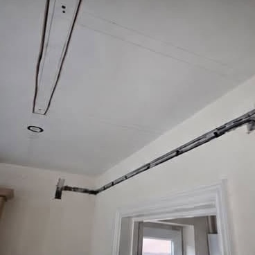 Open cable chases across ceiling and down wall above a door