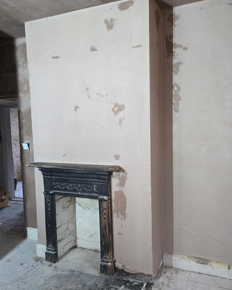 Chimney breast above a cast-iron fireplace, patched and prepped