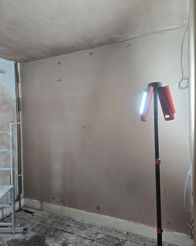 Freshly skimmed wall with a work light on a stand