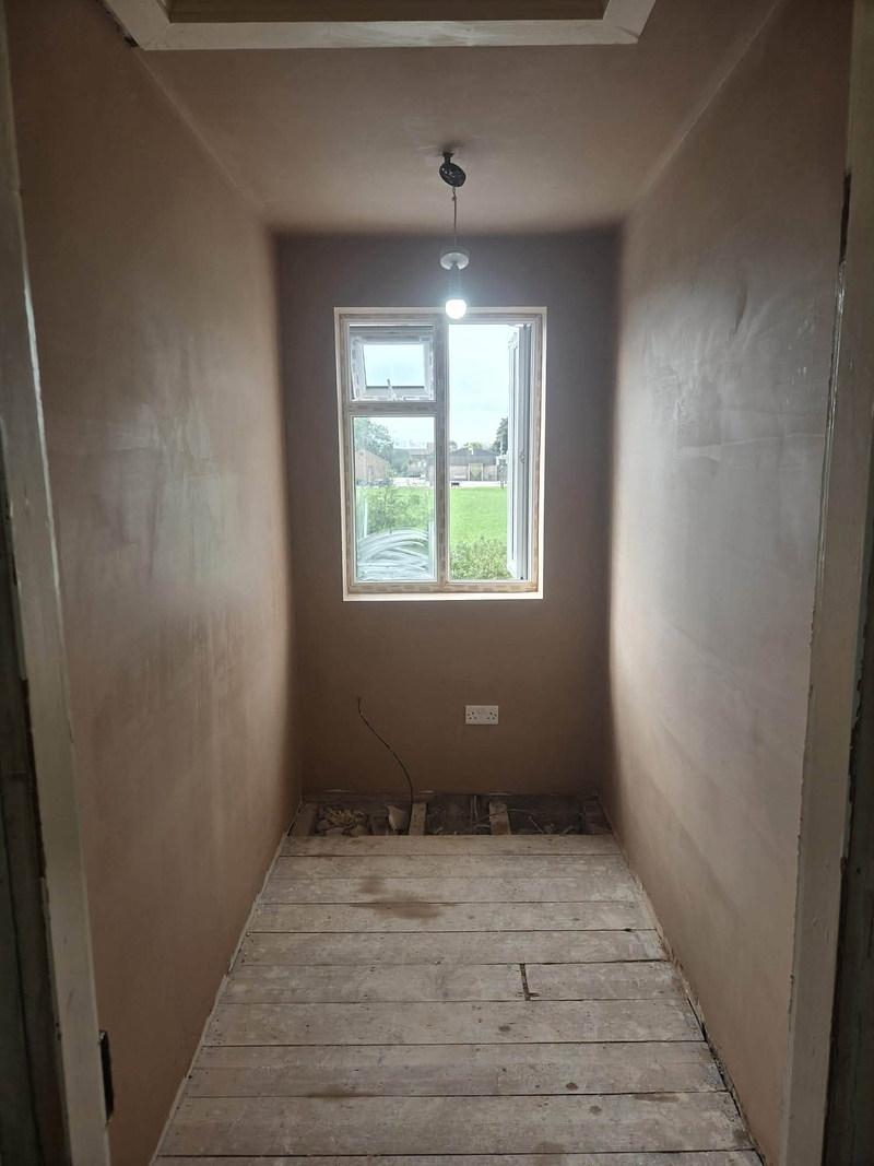 Narrow room with skimmed walls, window at the end and bare floorboards
